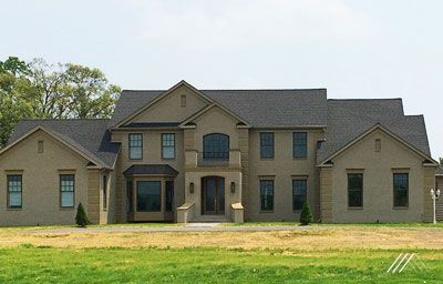 A large house is sitting on top of a lush green field.