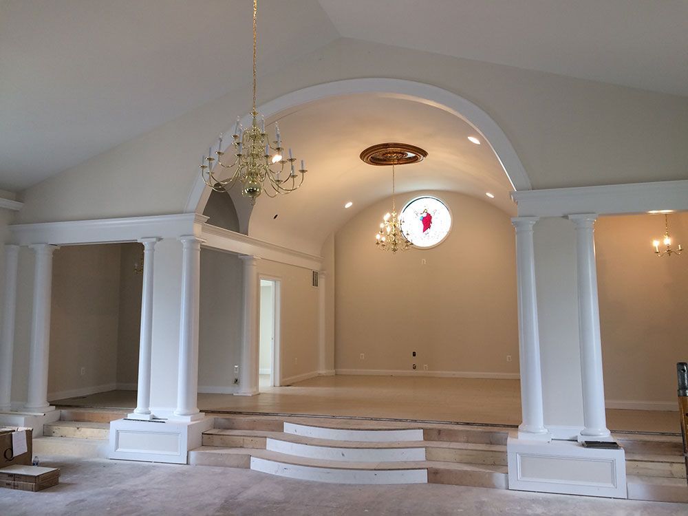 An empty room with columns and a chandelier hanging from the ceiling
