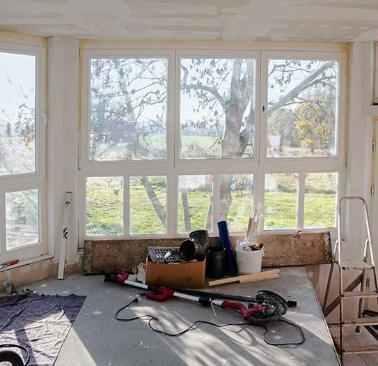 A room with a lot of windows and a box of tools on the floor.