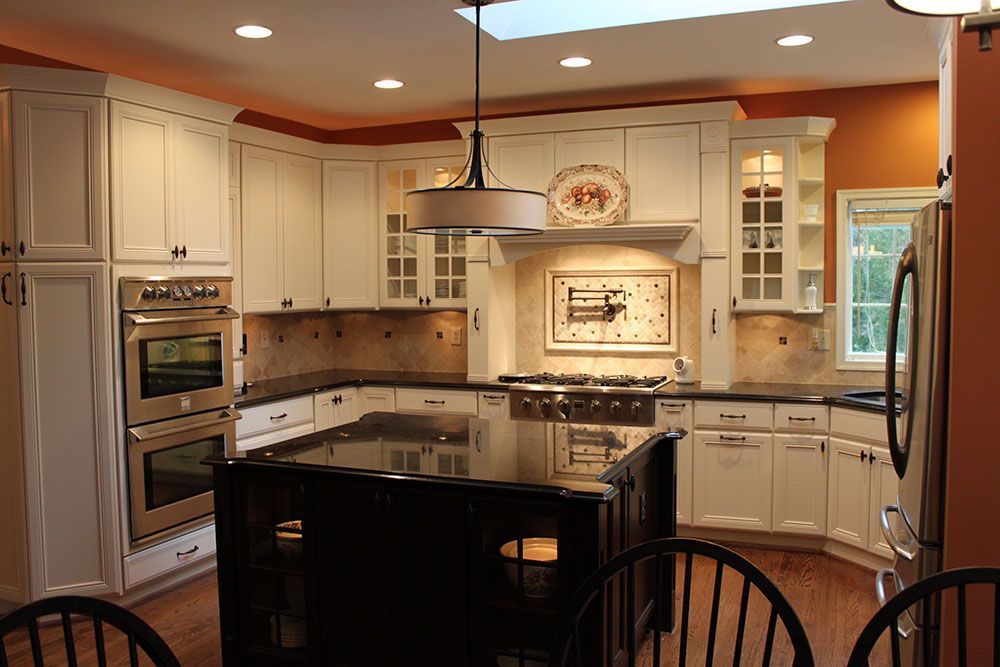 A kitchen with white cabinets and black counter tops