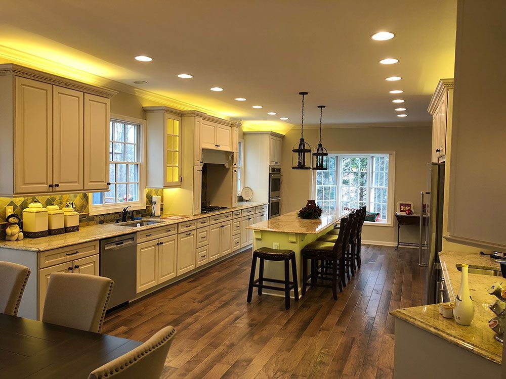 A large kitchen with white cabinets , hardwood floors , and a green island.