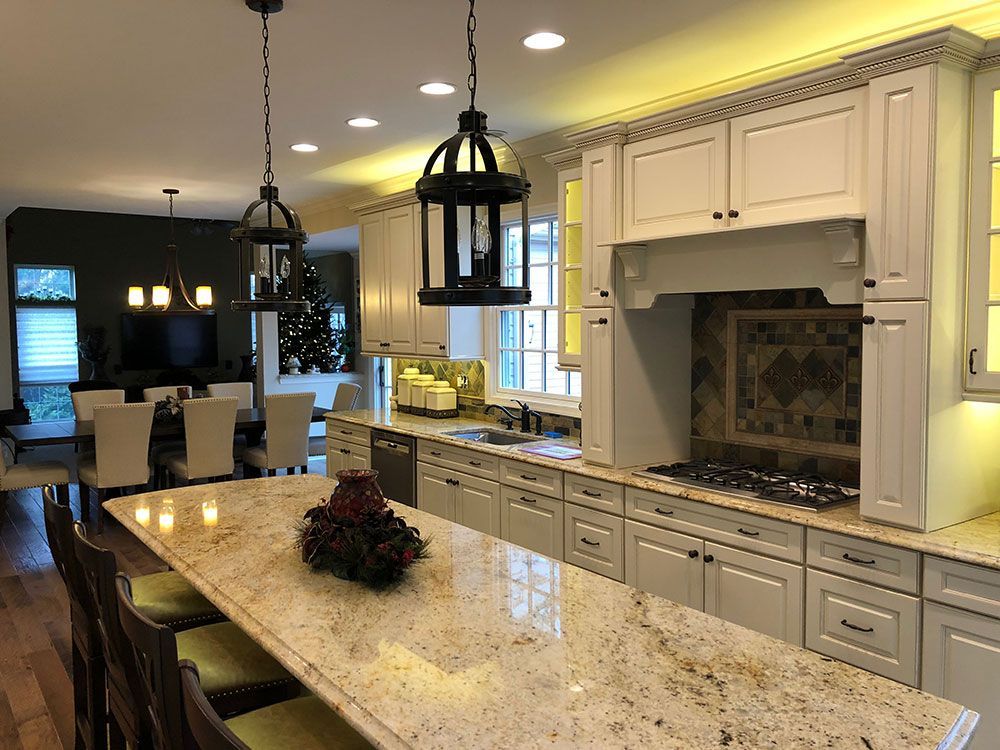 A kitchen with white cabinets and granite counter tops and a large island.