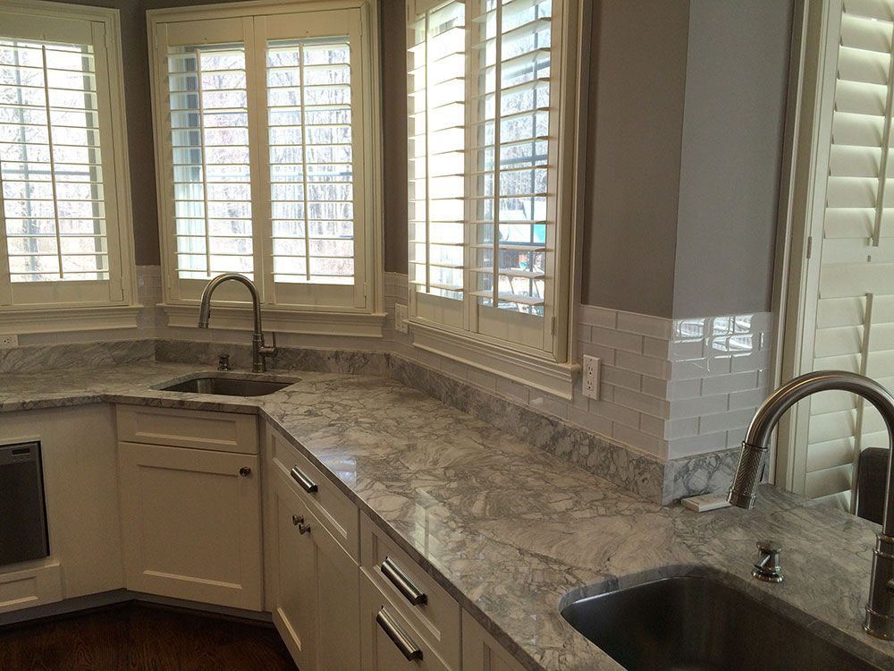 A kitchen with a sink , dishwasher , and shutters on the windows.
