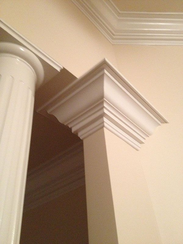A corner of a room with a pillar and crown molding