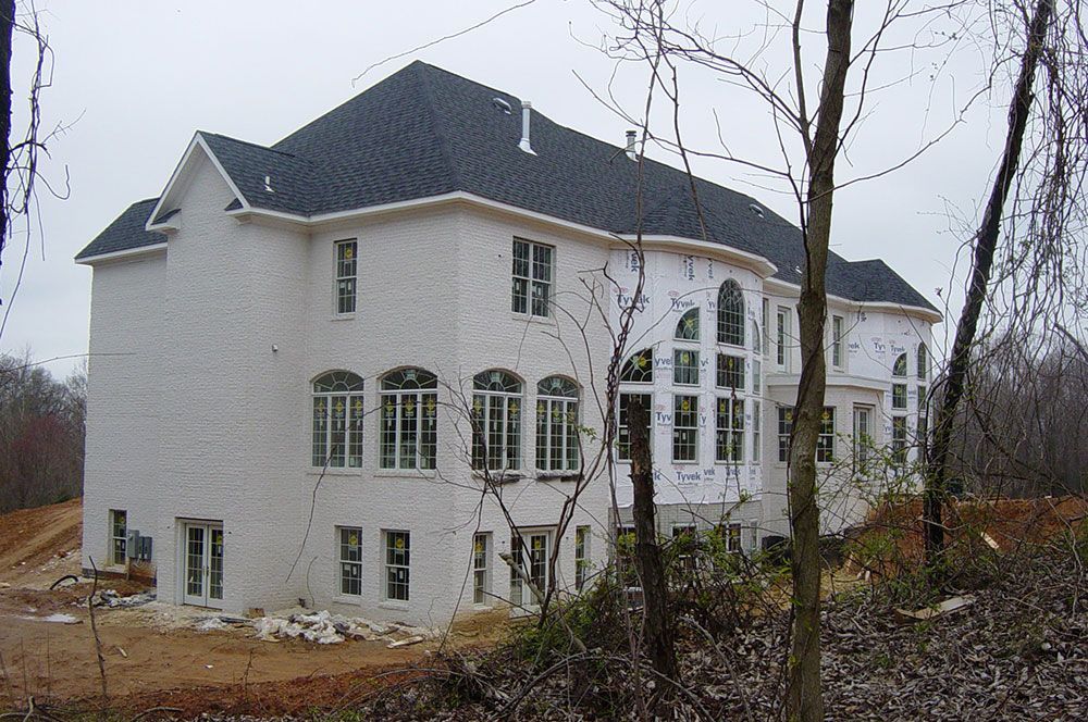 A large white house with a black roof is under construction