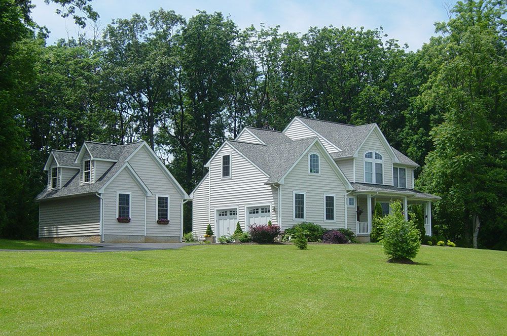 A large white house sits in the middle of a lush green field