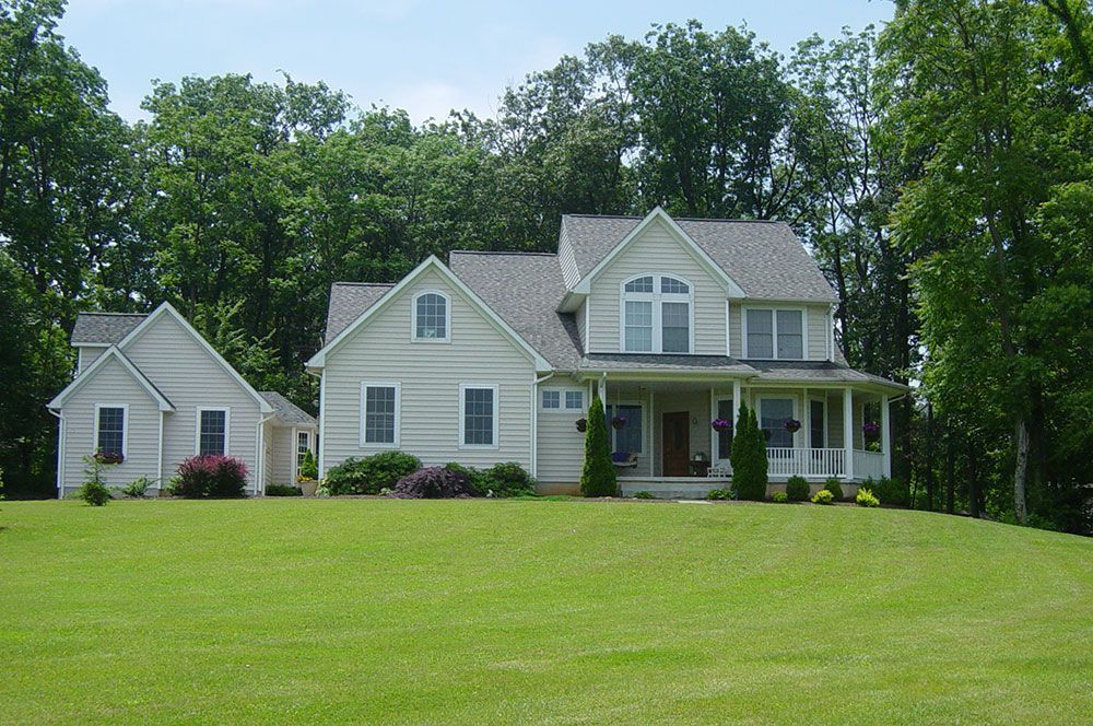 A large white house sits on top of a lush green hillside