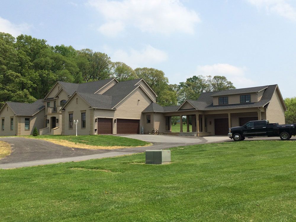A black truck is parked in front of a large house