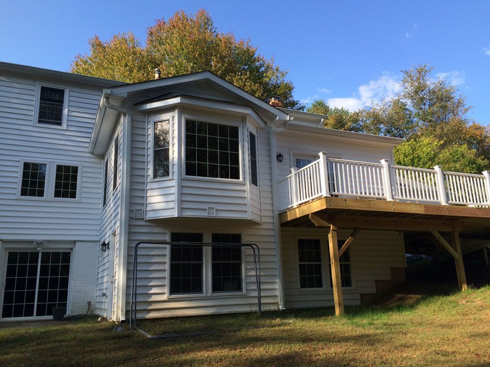 A large white house with a large deck in the backyard