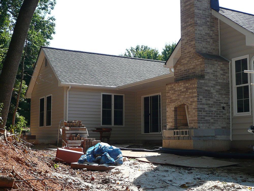 A house under construction with a brick fireplace in the backyard