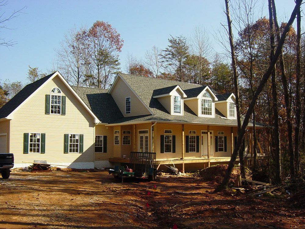A large house with a large porch is surrounded by trees
