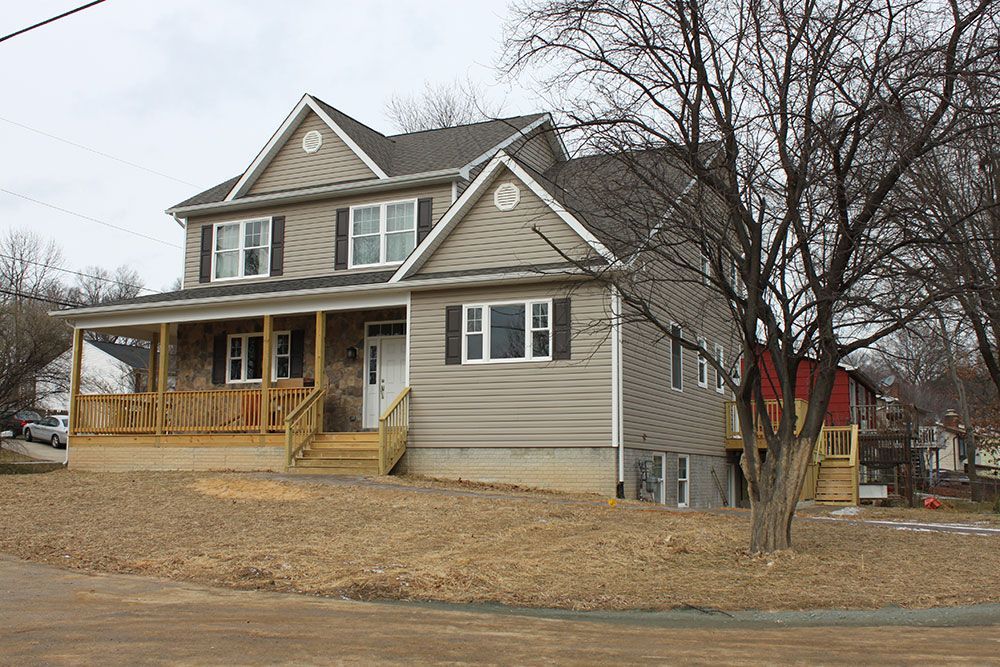 A large house with a porch and a tree in front of it
