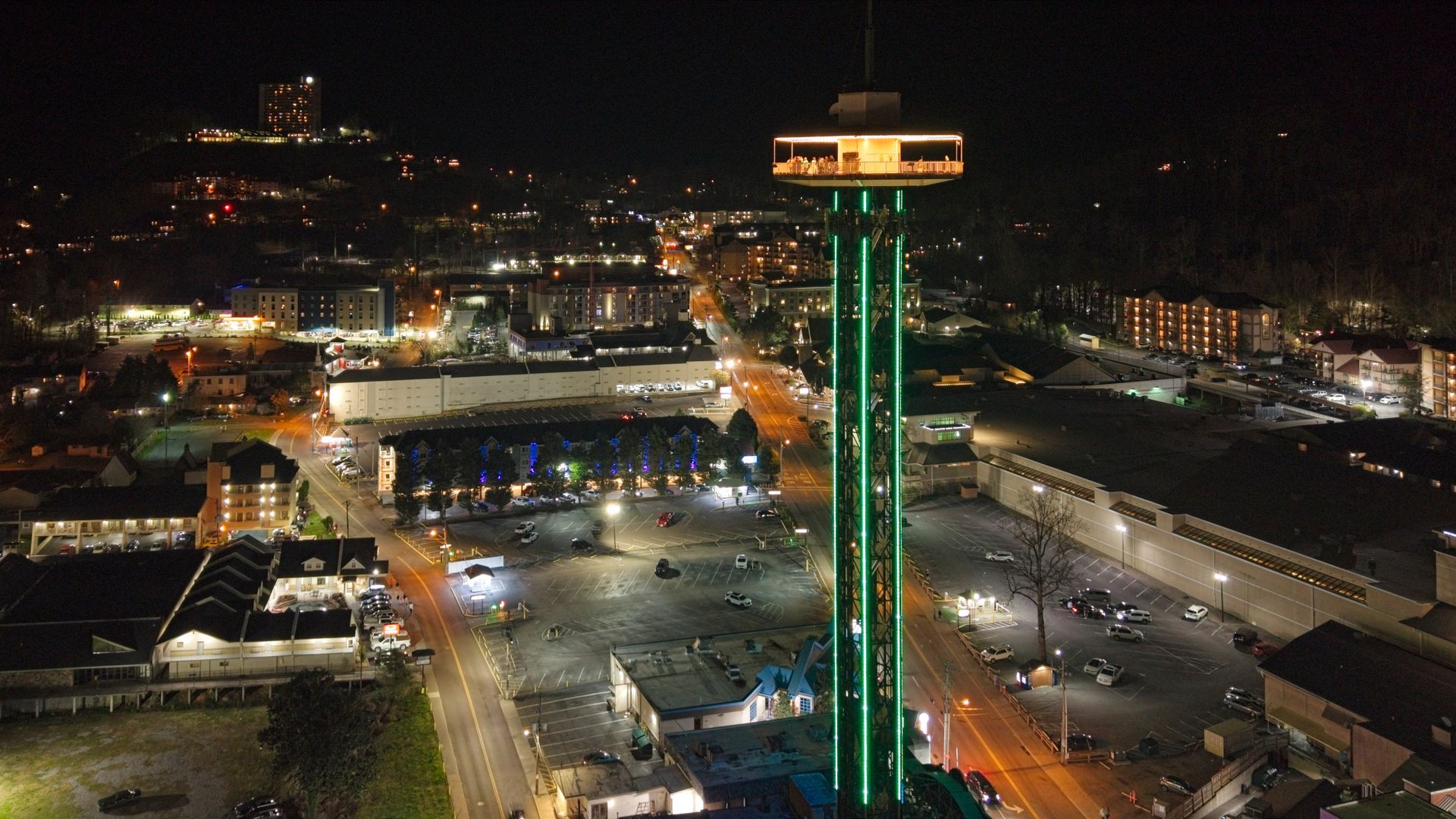 Nighttime city view with a lit green tower overlooking buildings and streets