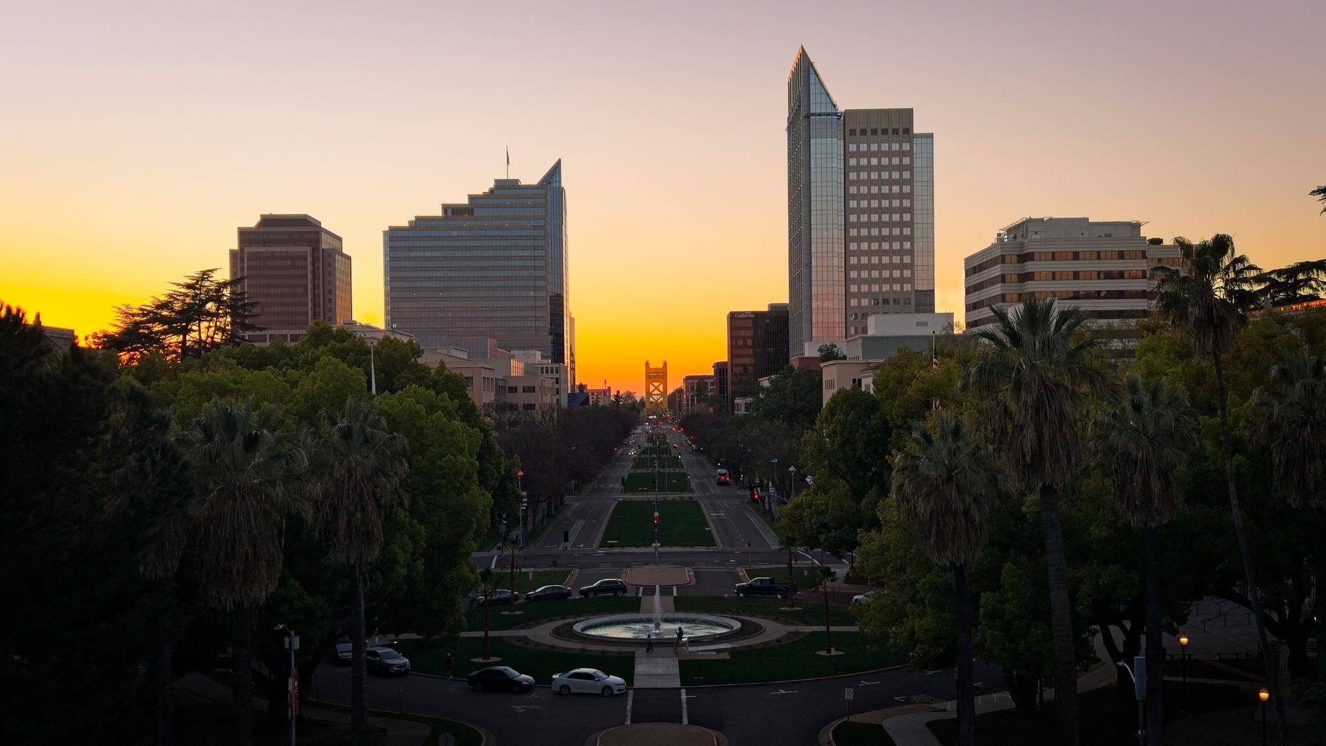 City skyline at sunset with high-rise buildings and a park in the foreground