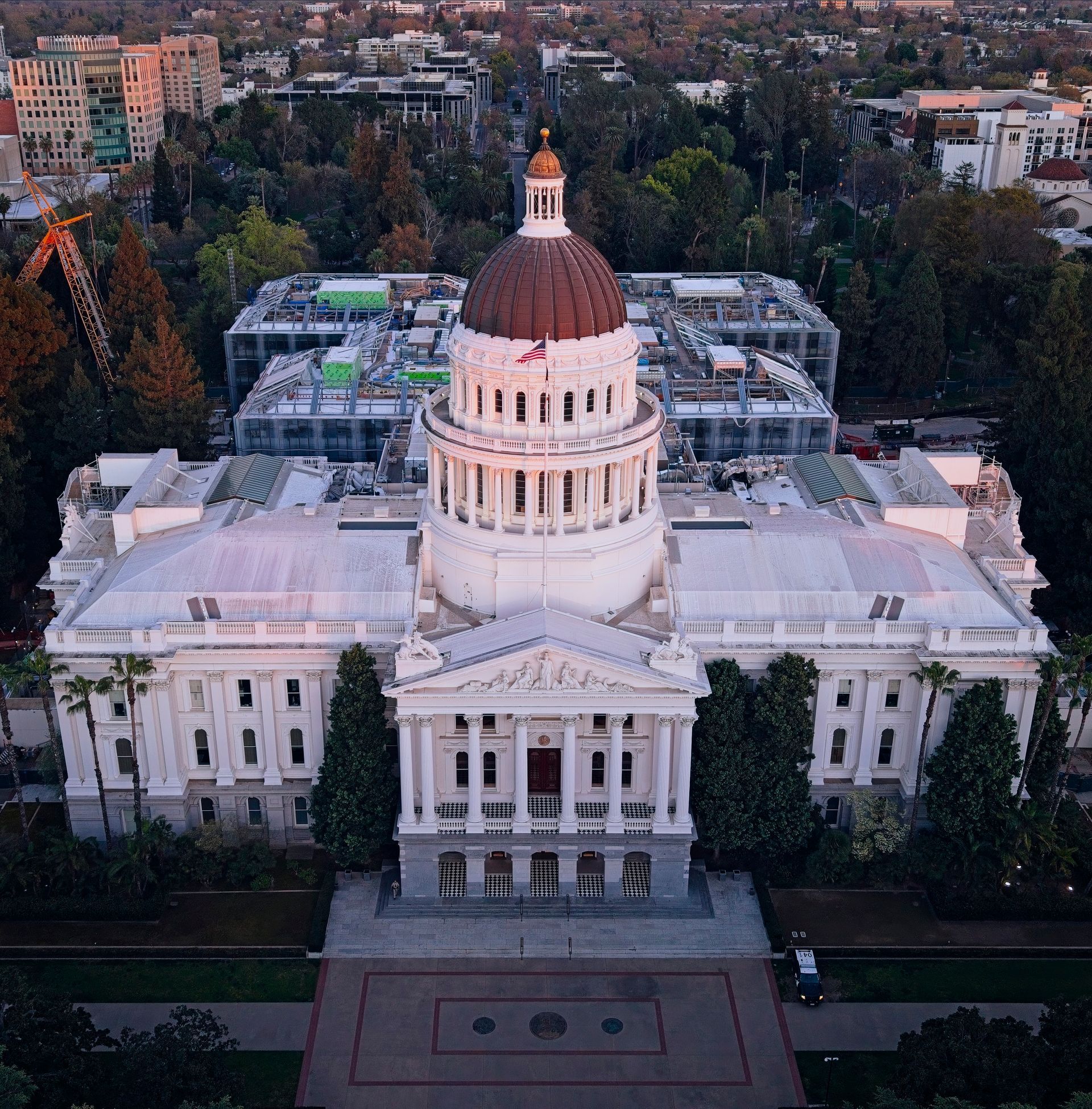 Aerial view of a white domed capitol building with a columned facade at dusk.