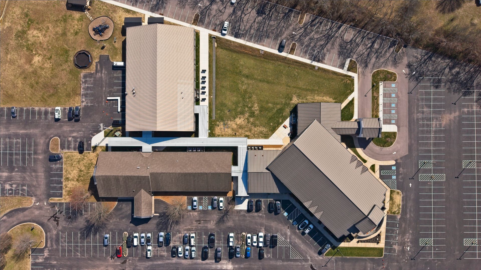 Aerial view of a church campus with multiple buildings, parking lots, and a grassy courtyard.