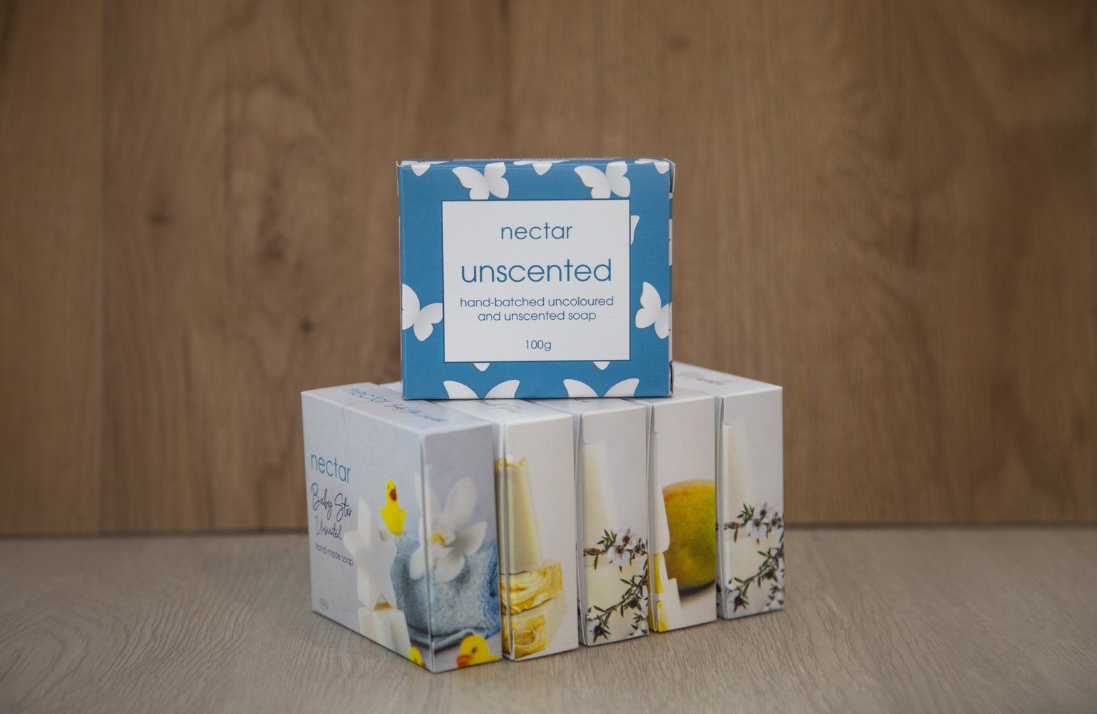 Two boxes of soap. One blue, butterfly-themed, atop a larger box with bird and floral designs on a wooden background.From Excel In Print Auckland. 