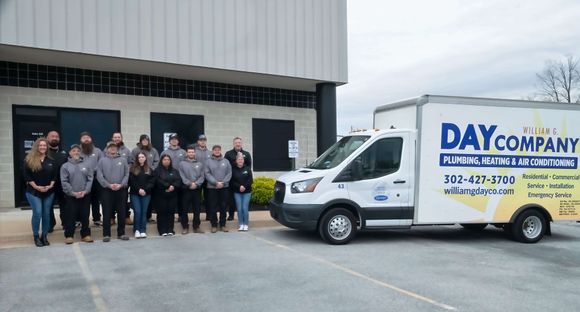 Staff posing beside a white Day Company service van outside a building