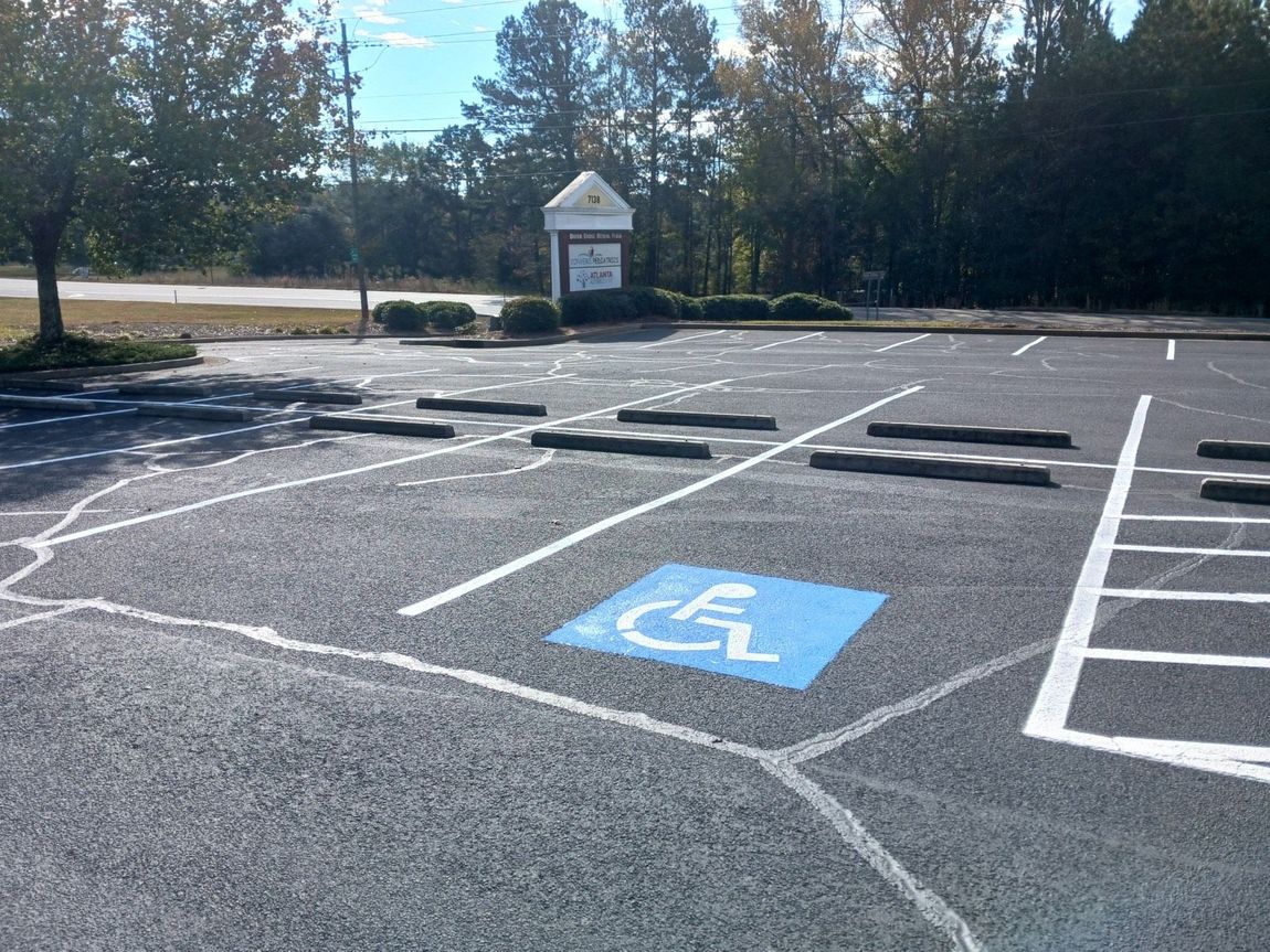 Parking lot with an accessible parking space marked with a wheelchair symbol, and parking bumpers.