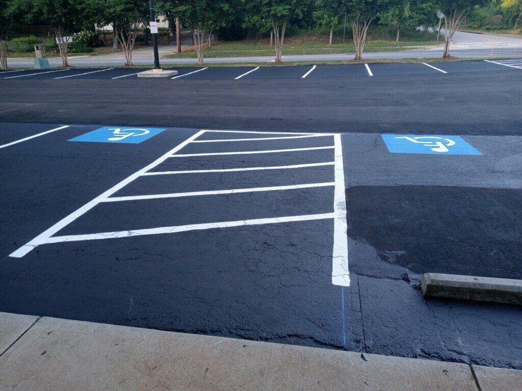Parking lot with designated accessible parking spaces marked with blue symbols and white lines.