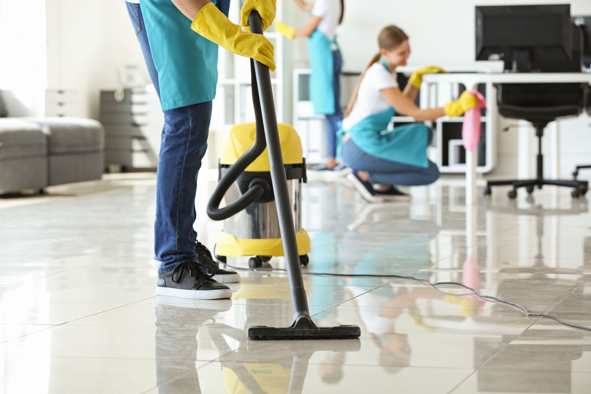 Office cleaners mopping a glossy floor near desks and a computer monitor