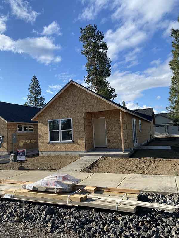 New brick house under construction with unfinished front porch and materials in the yard
