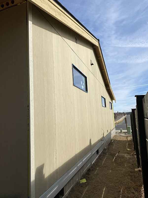 Side view of a beige building with small windows under a blue sky.
