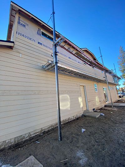 Side view of a beige building with pipes and a gravel area under a clear blue sky
