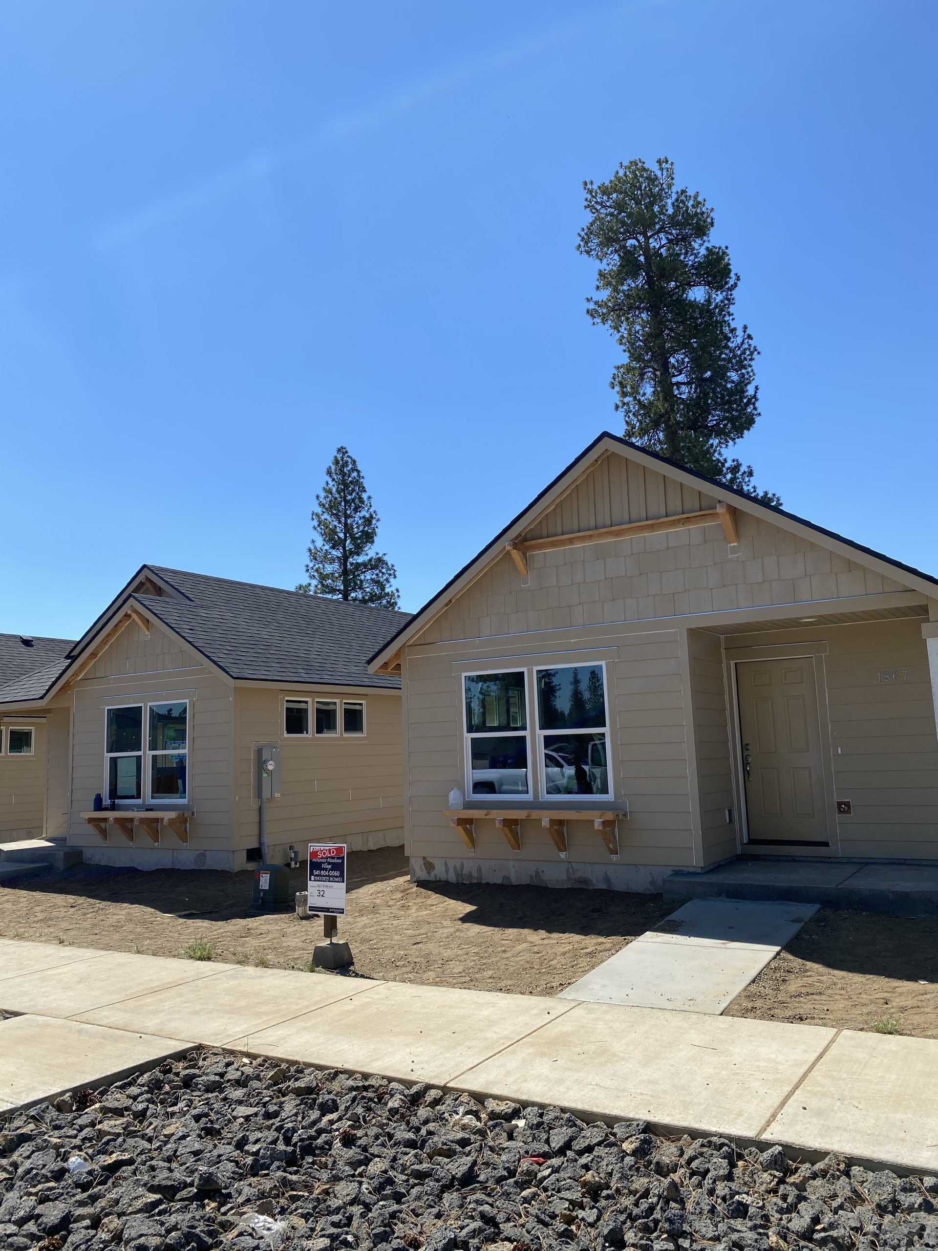 New beige house under construction with a small front porch and clear blue sky
