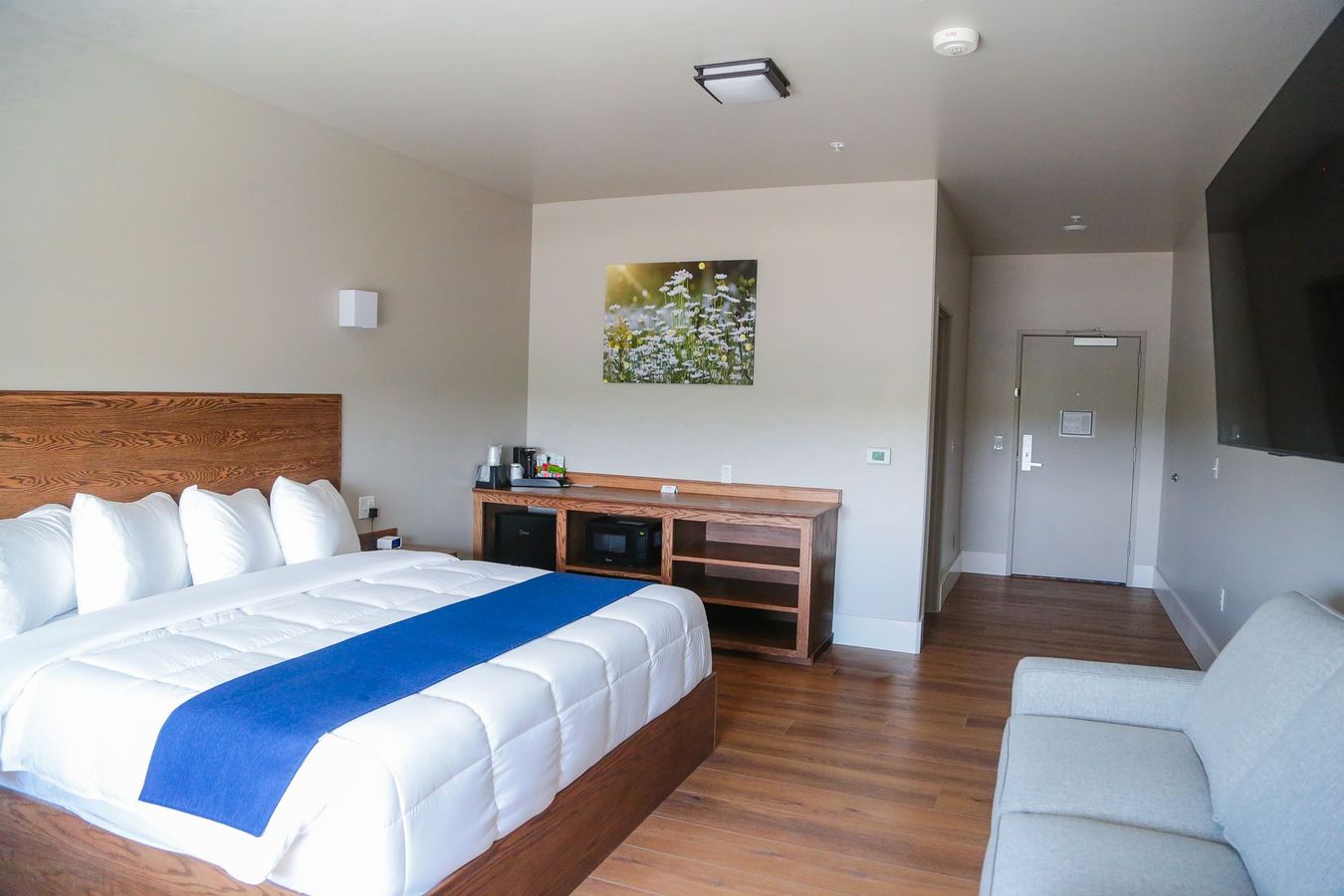 A hotel bedroom with a white bed, chair, and lamp.