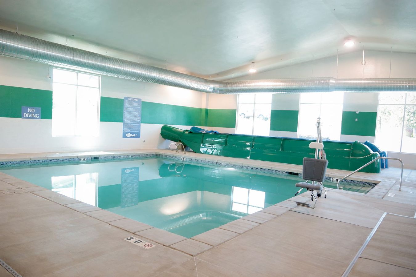 Indoor swimming pool with clear water, white ceiling, and a covered pool lane divider at the far end
