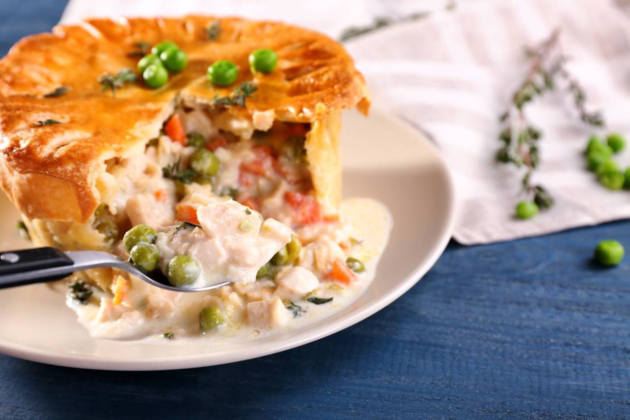 Chicken pot pie on a plate, with a spoonful of the creamy filling being lifted.