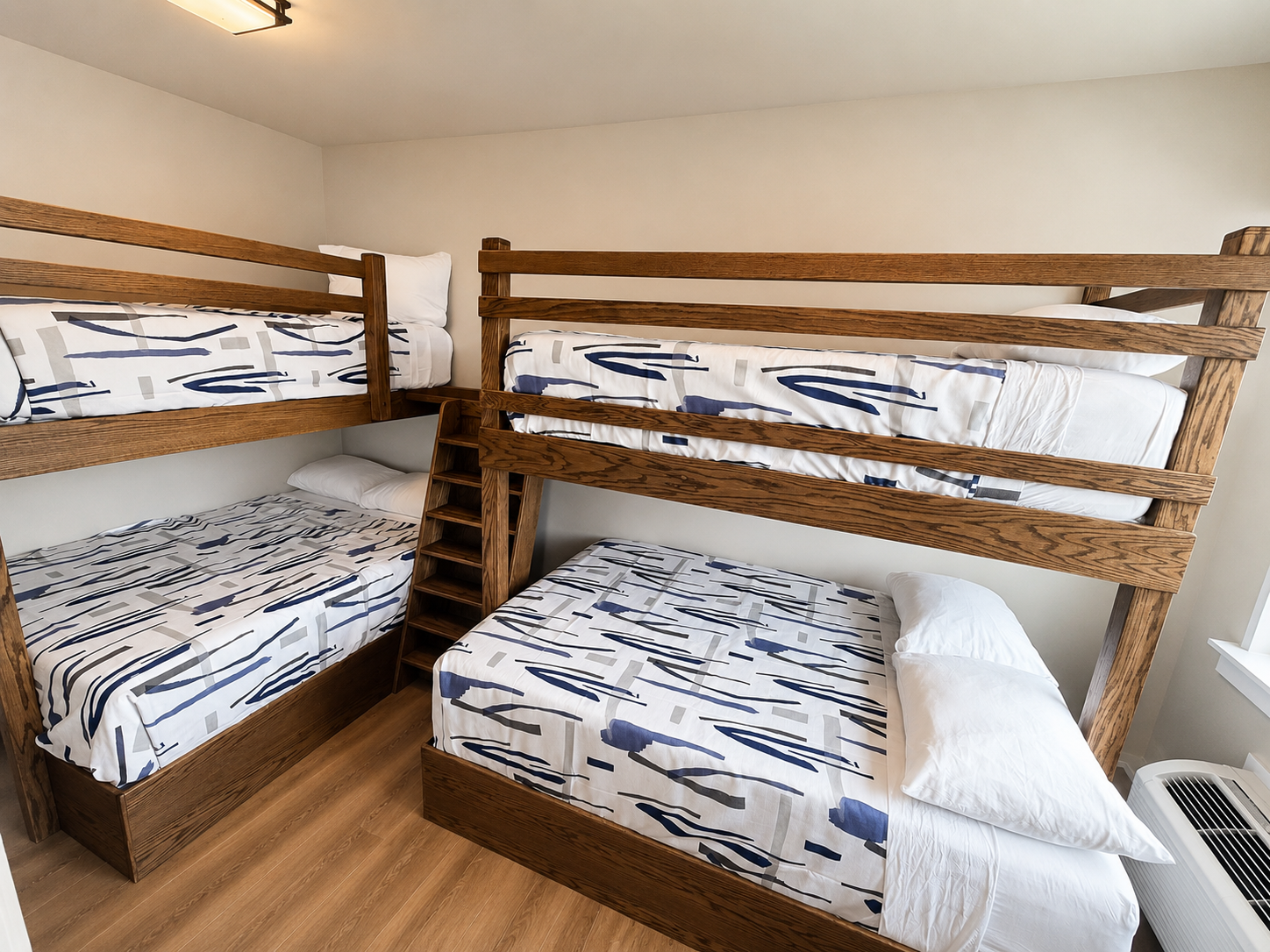 Two wooden bunk beds in a small room with white and blue patterned bedding and wood floors