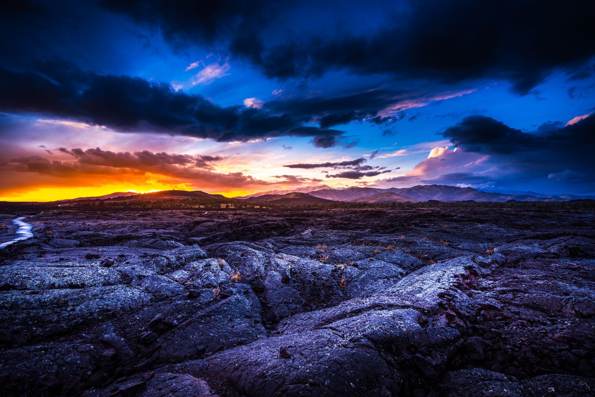 Dramatic sunset over a rocky landscape with blue clouds and glowing orange horizon