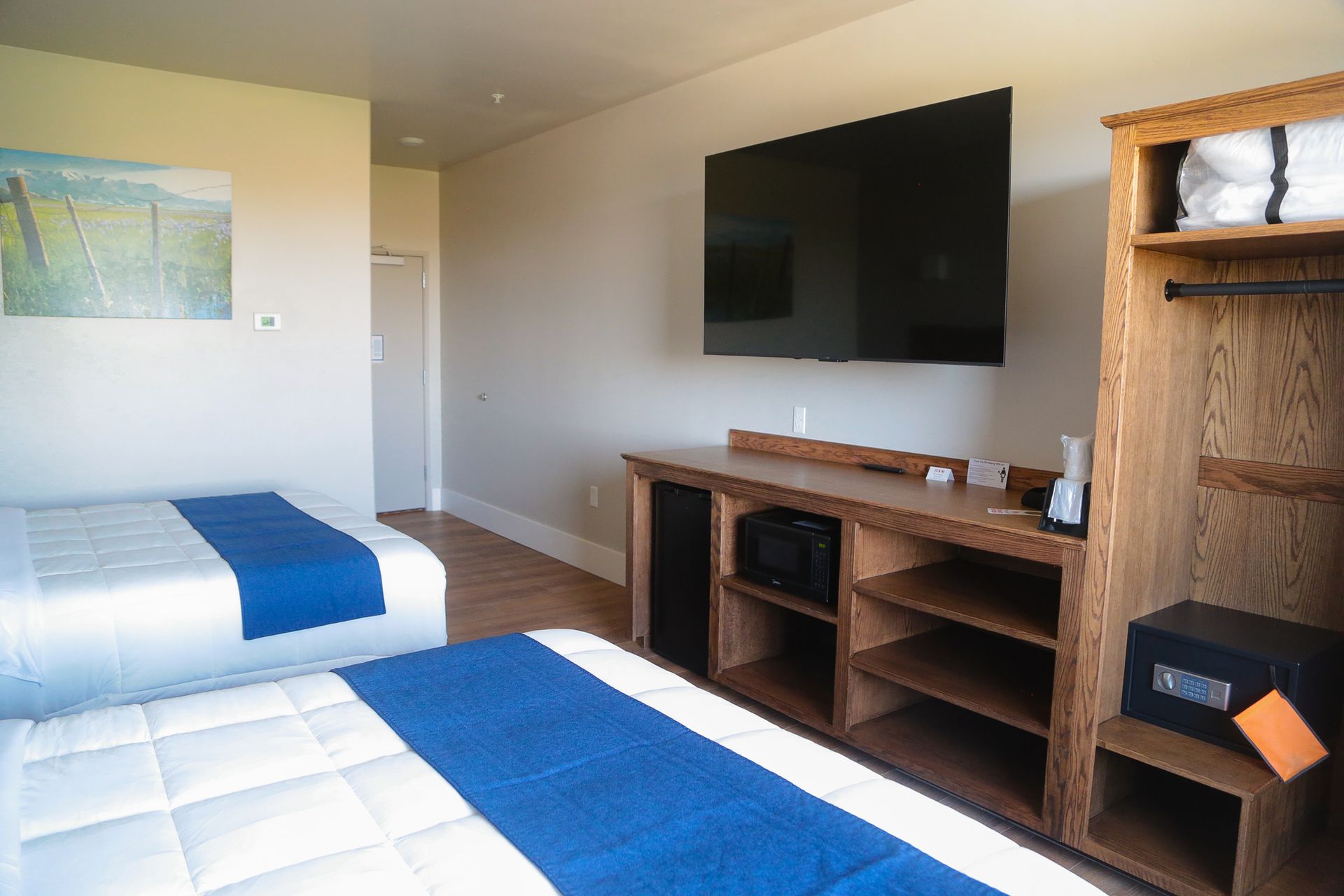 Bedroom with two twin beds, wall-mounted TV, and wooden shelving unit.