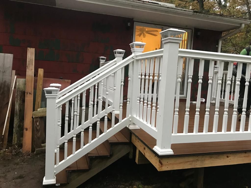 White wooden porch ramp and railing attached to a house, with steps on the left side