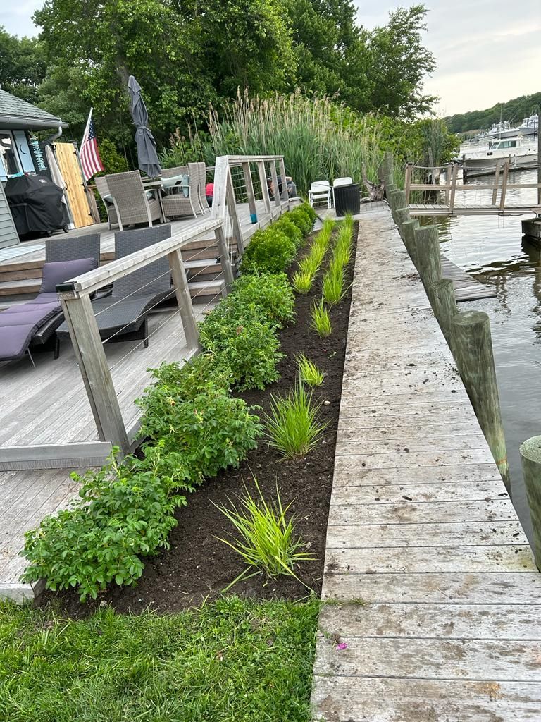 Dockside walkway with fresh green shrubs planted beside a stone seawall and water channel