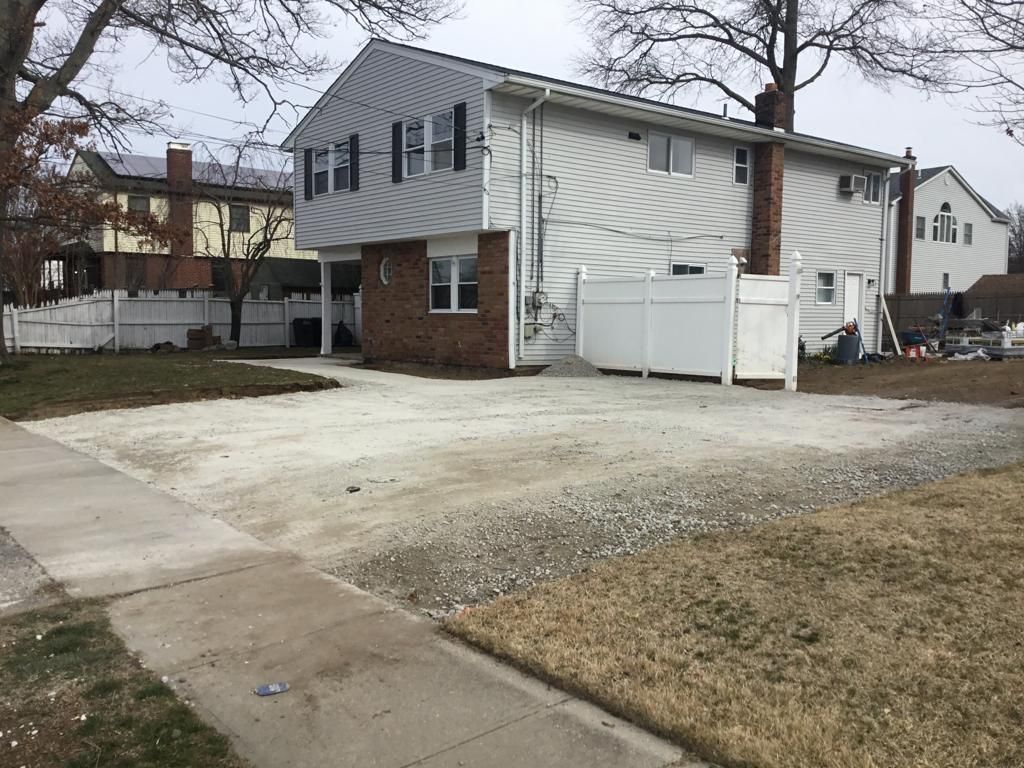 Residential house with a gravel driveway, concrete sidewalk, and bare winter lawn.