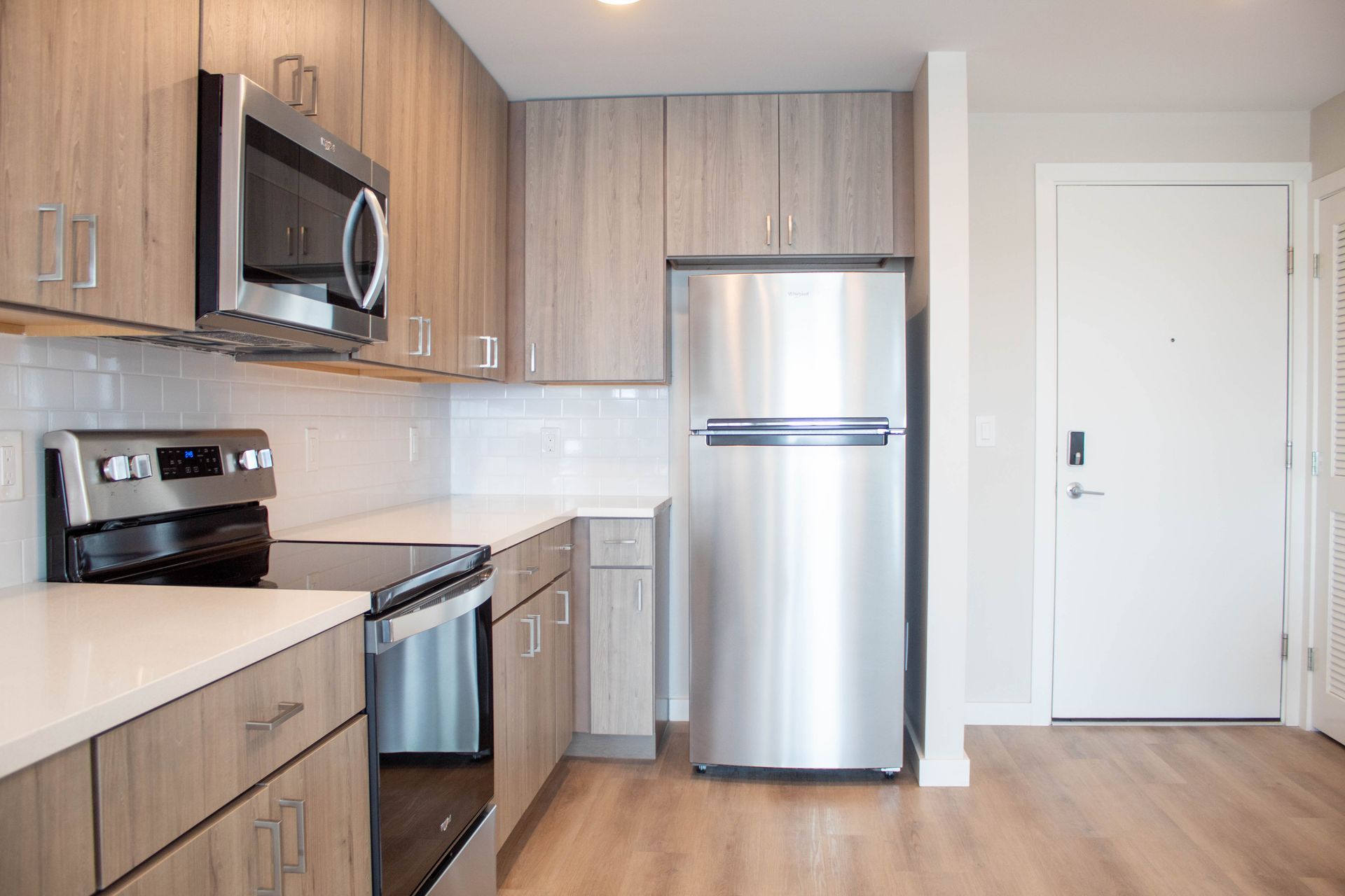 Modern kitchen with stainless steel appliances and light wood cabinets.