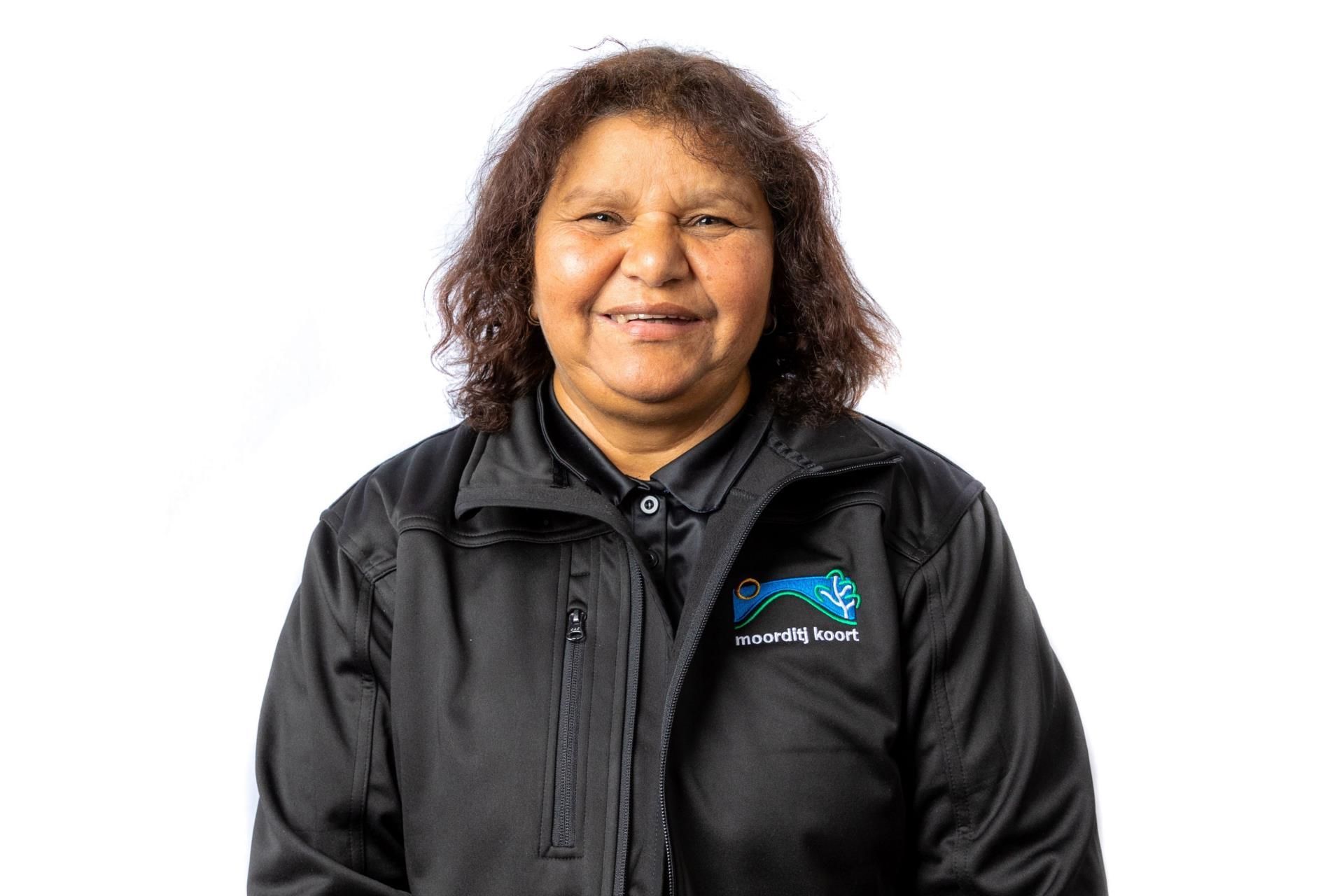 A woman is wearing a black jacket and smiling for the camera.