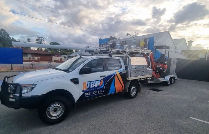 A white truck with a trailer attached to it is parked in a parking lot.