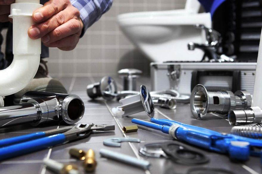 A plumber is fixing a sink in a bathroom.