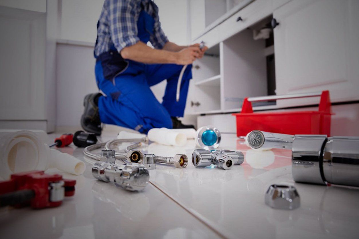 A plumber is fixing a sink in a kitchen.