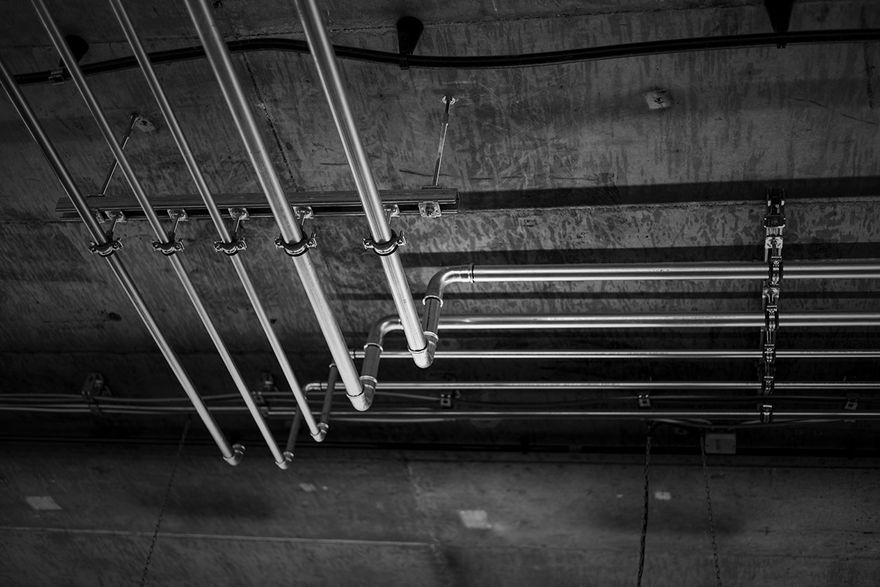 A black and white photo of a bunch of pipes hanging from the ceiling.