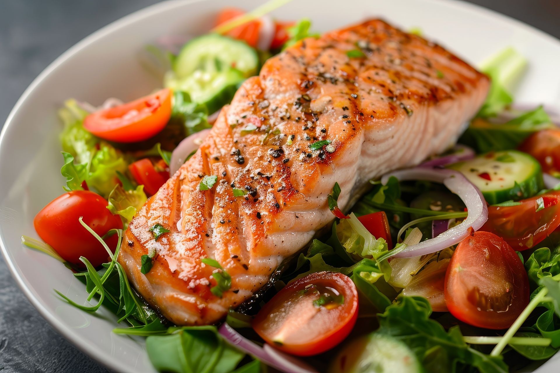 A white plate topped with a piece of salmon and vegetables.