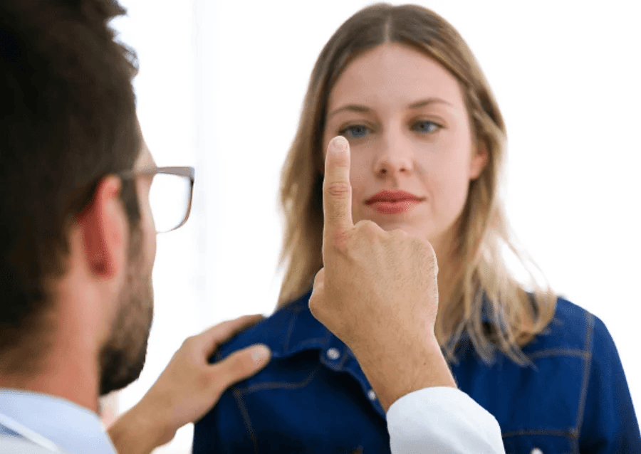 Eye exam with clinician checking a woman's vision using a handheld occluder