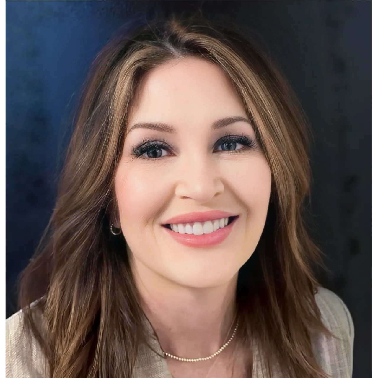 Smiling woman with long brown hair against a dark blue background