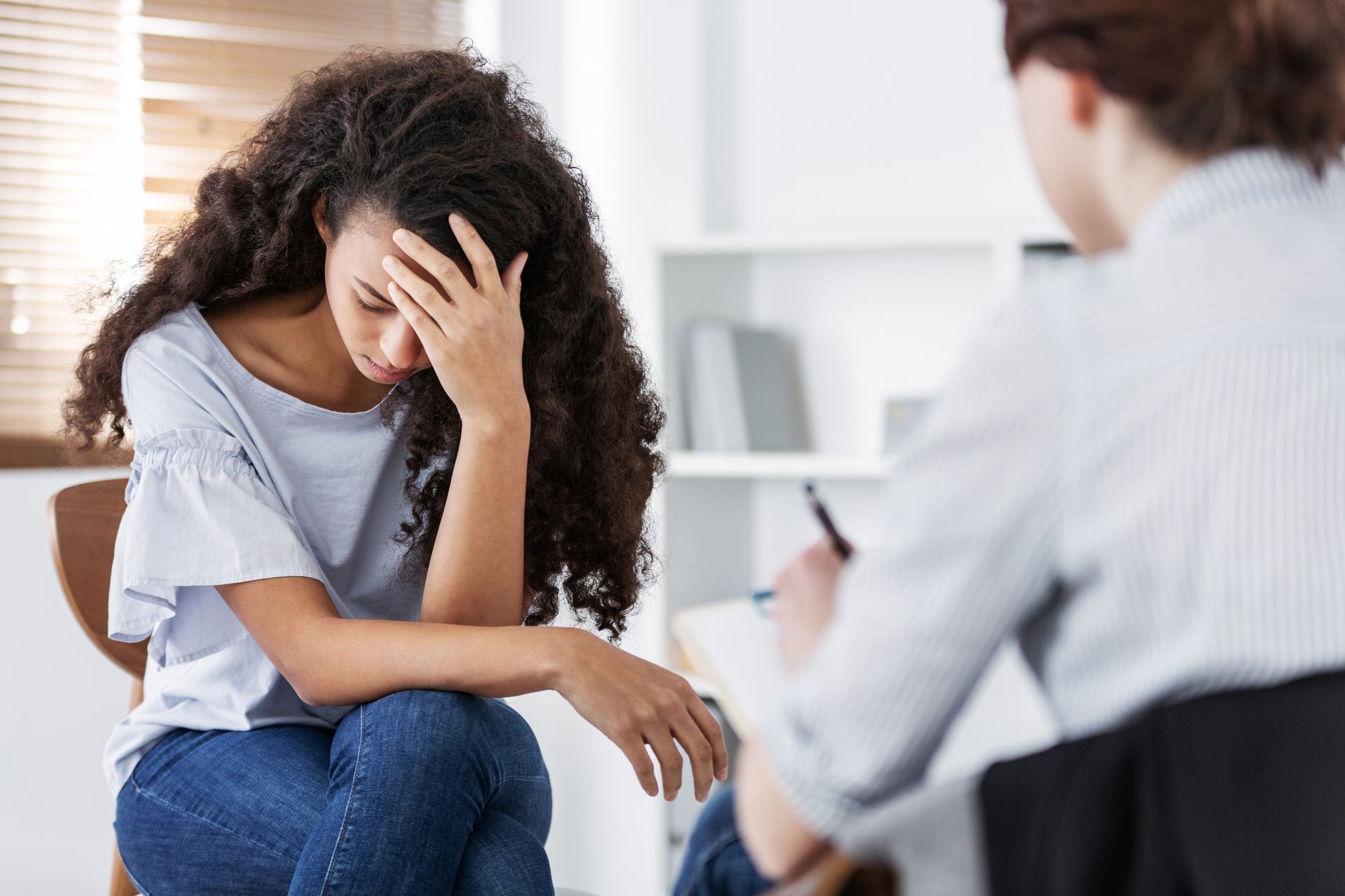 Distraught person sitting with head in hand during a counseling session