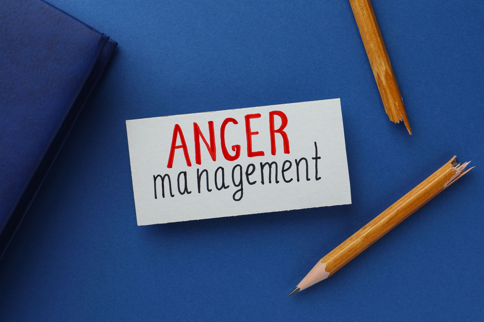 Anger management note on blue desk with pencils and notebook