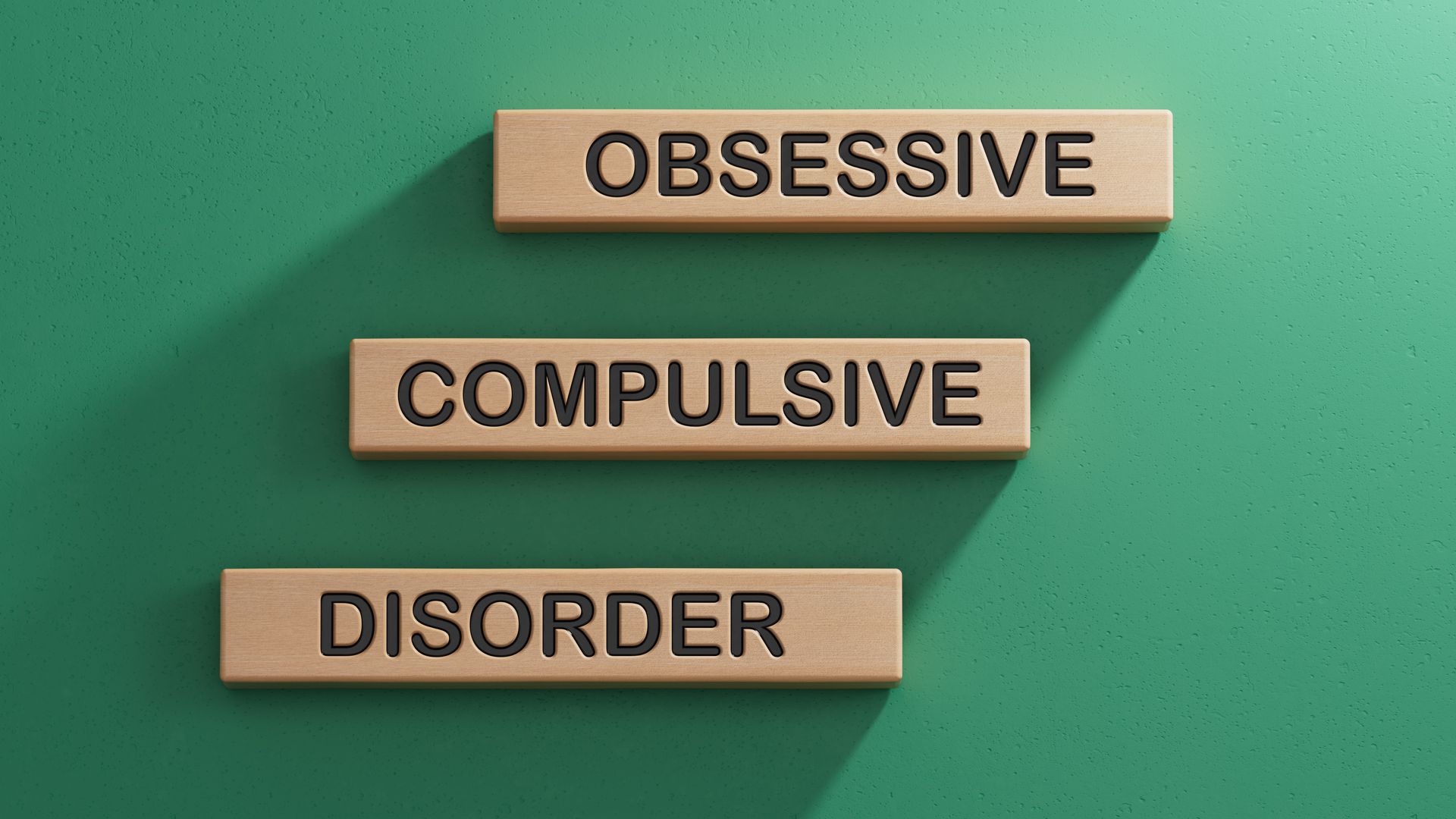 Wooden blocks spelling “obsessive compulsive disorder” on a green background
